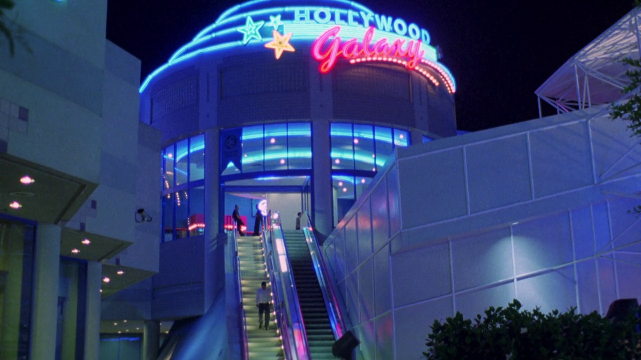 好莱坞银河购物中心霓虹灯“好莱坞银河”的向上角度。在楼梯和自动扶梯上的人。大楼内的霓虹灯。商场中庭的穹顶天花板。视频下载