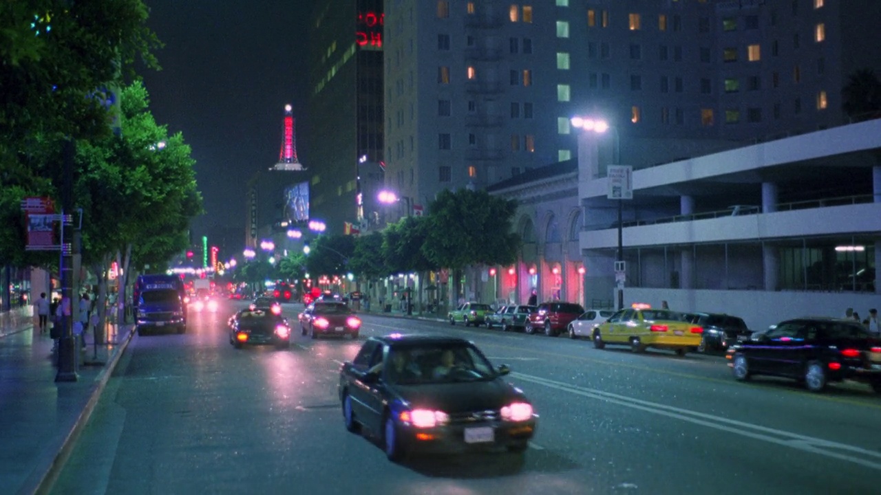 从好莱坞大道向右向左平移。好莱坞银河购物中心的霓虹灯招牌“好莱坞银河”。街上停着汽车，人们走在好莱坞星光大道上。汽车驾驶。街灯一字排开。在楼梯和自动扶梯上的人。霓虹灯闲逛视频下载