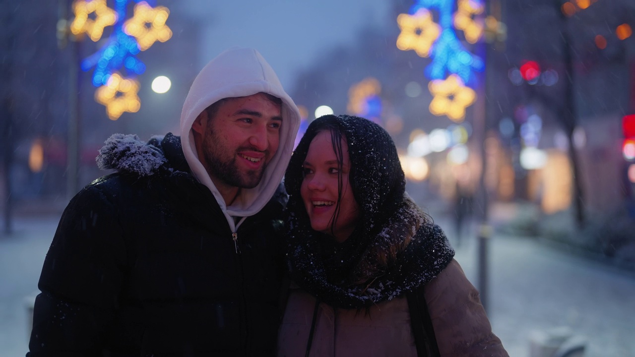 年轻的夫妇走在城市，而在下雪的冬天的晚上视频下载