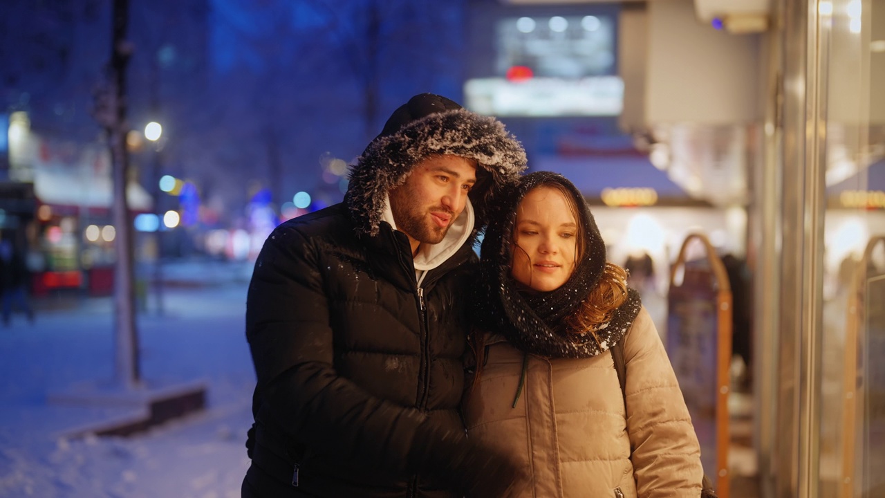 年轻的情侣约会和逛街，在下雪的夜晚城市视频素材
