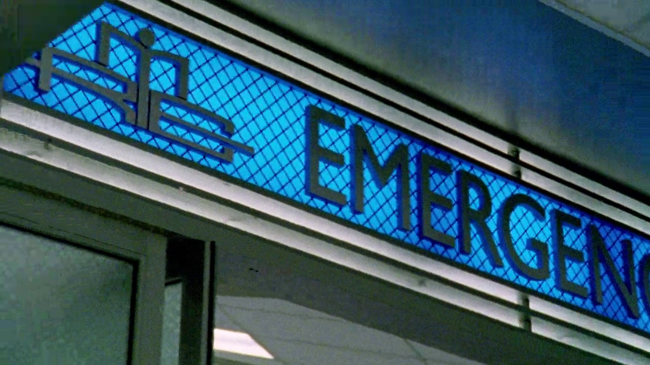 蓝色标志牌上写着"急诊室"可能是医院或者急诊室镜头向下平移到有窗户的走廊。视频下载