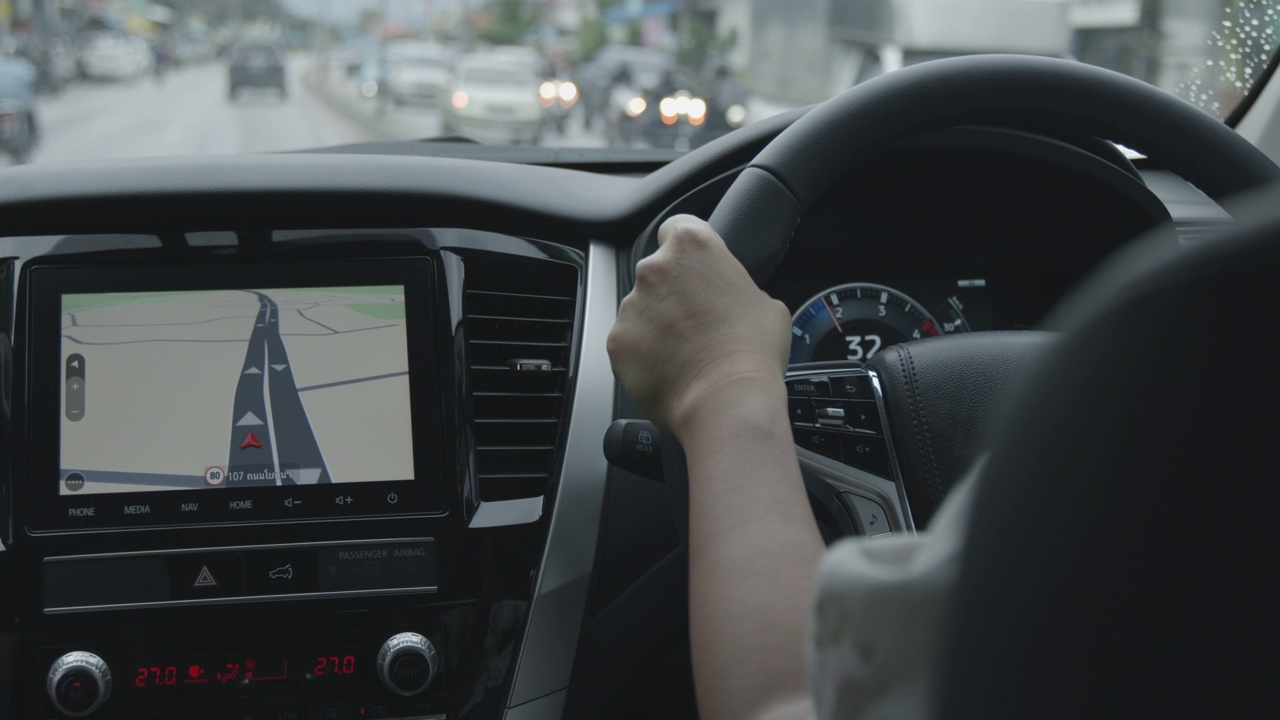 女子驾驶一辆带有地图显示的汽车在城市道路上导航。视频下载