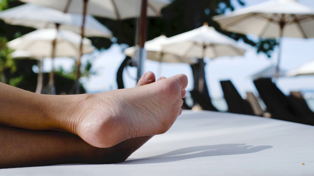 近光脚交叉腿躺在海滩床椅子在海上视频下载