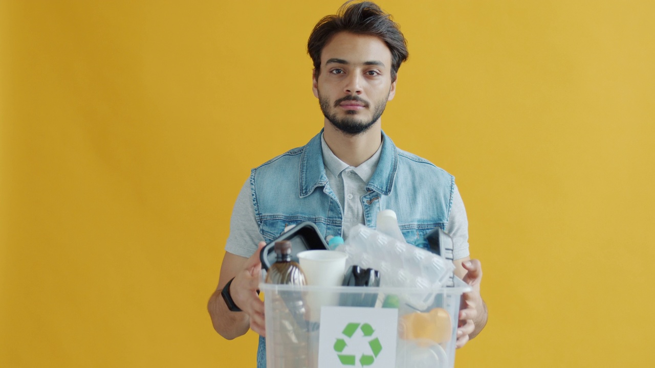 印度男子的肖像，拿着回收的塑料垃圾盒，看着相机视频下载
