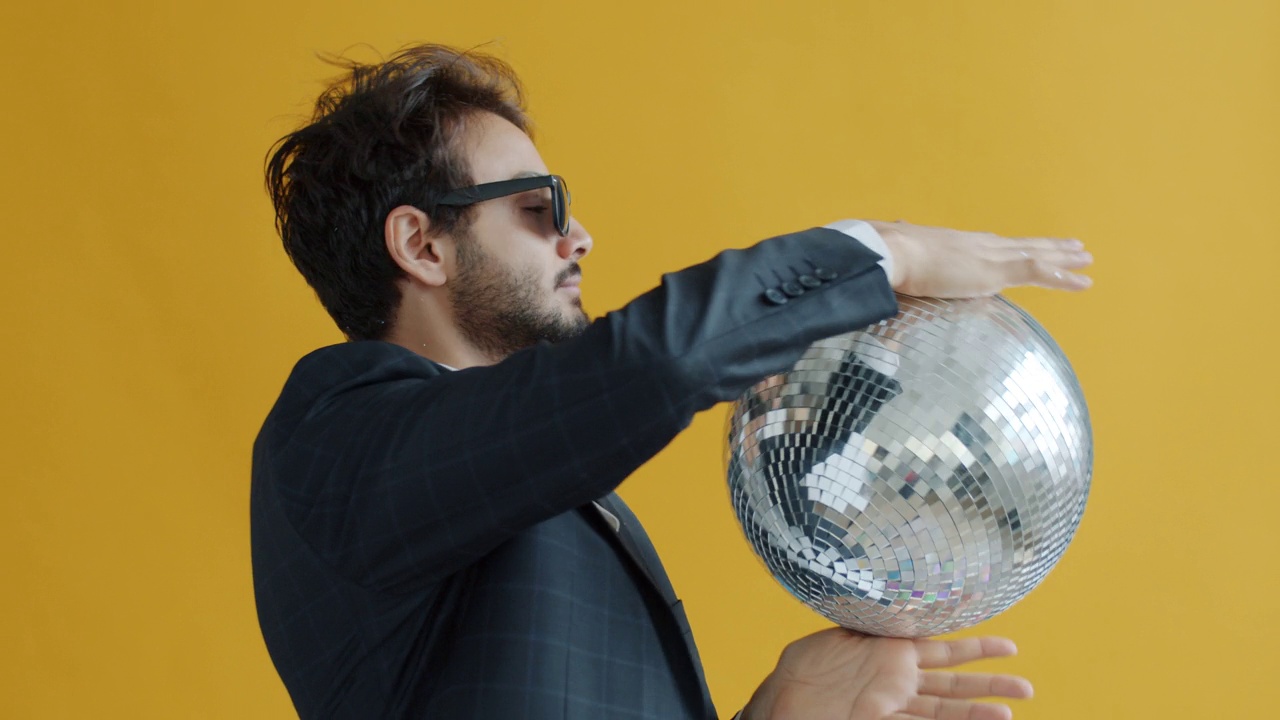 快乐的阿拉伯人跳舞的慢动作肖像与迪斯科球在黄色的背景视频素材