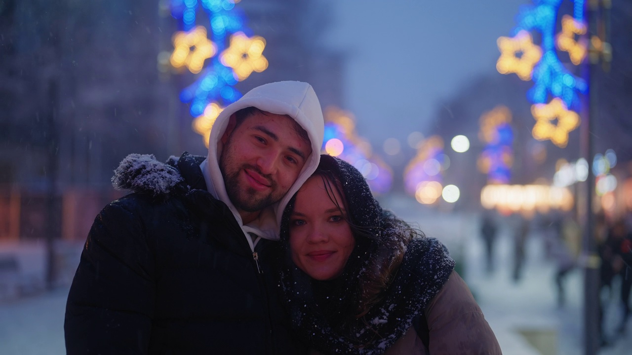 冬夜飘雪，城市里年轻夫妇的肖像视频下载