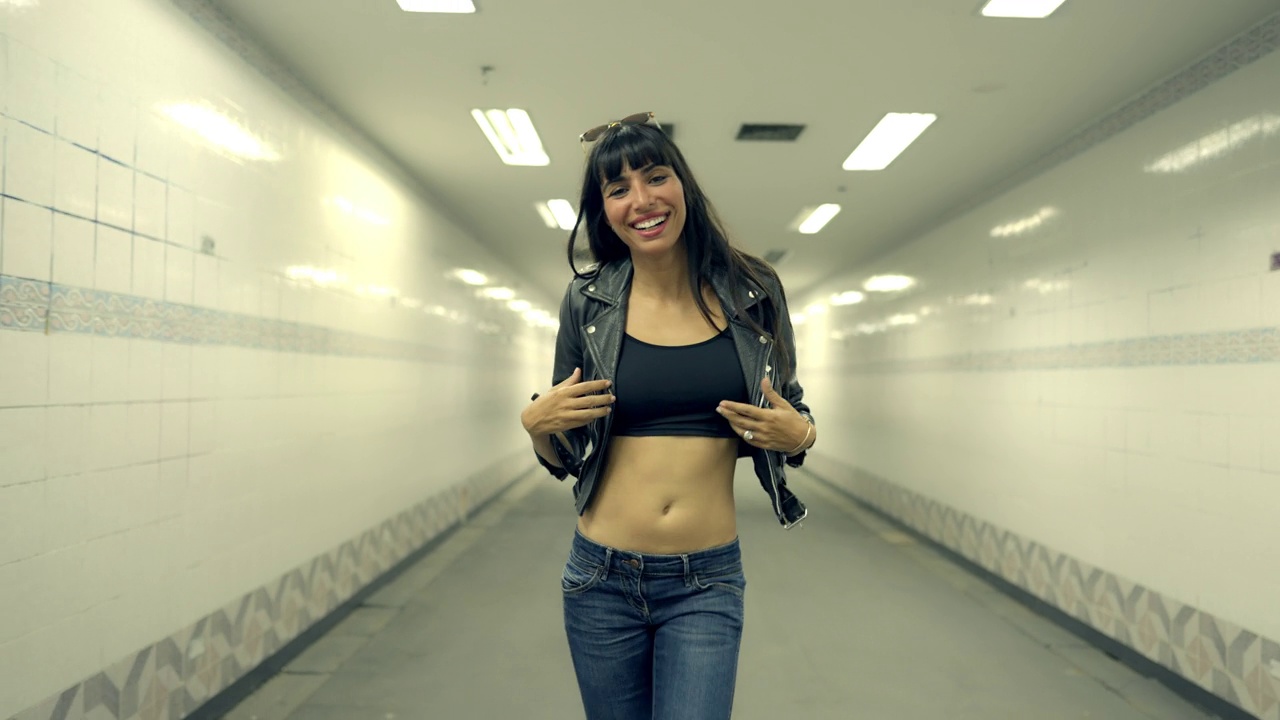 4K肖像的时尚西班牙裔妇女走在十字街隧道在城市的夜晚。视频下载
