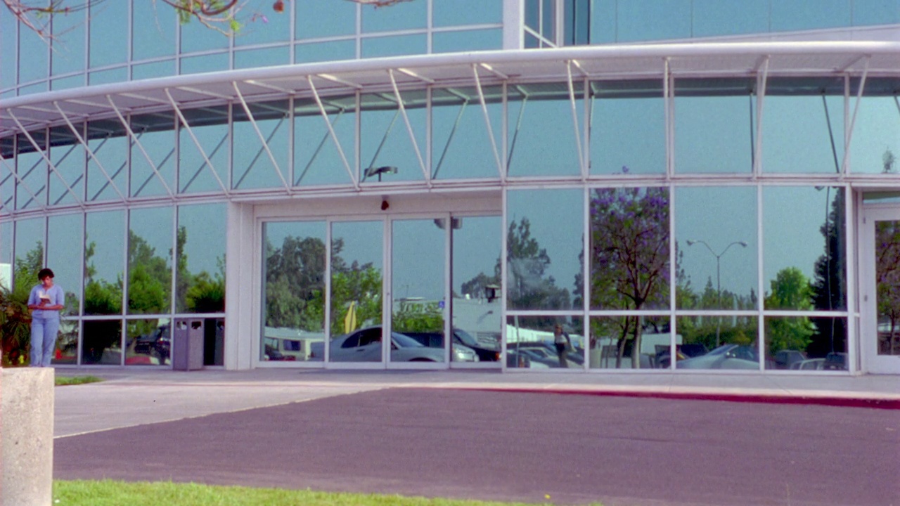 中角的多层洛杉矶会议中心大楼。见前面的反光玻璃。在前景中看到一辆银色的汽车驶过。视频下载