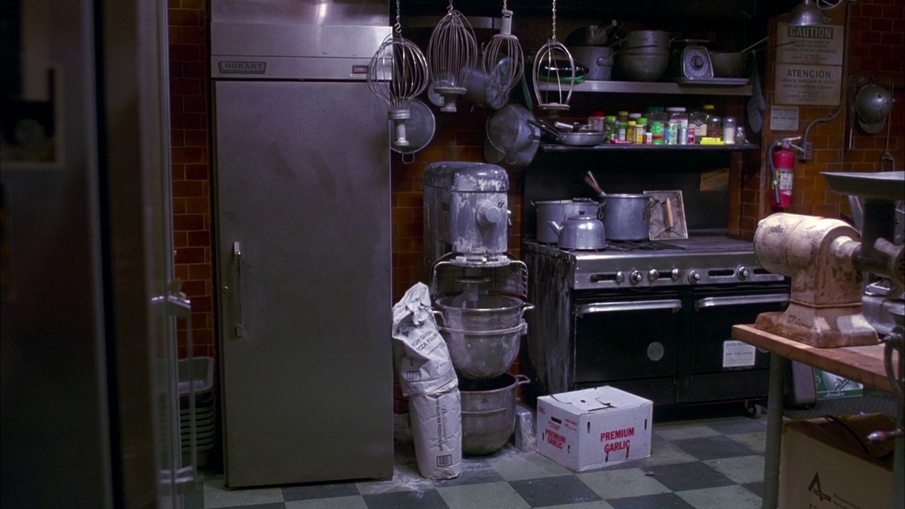 厨房左侧和右侧的平底锅和几个罐头，用具和炊具堆放在架子上或柜台上。参见炉灶和冰箱。在整个镜头中继续来回平移。视频素材