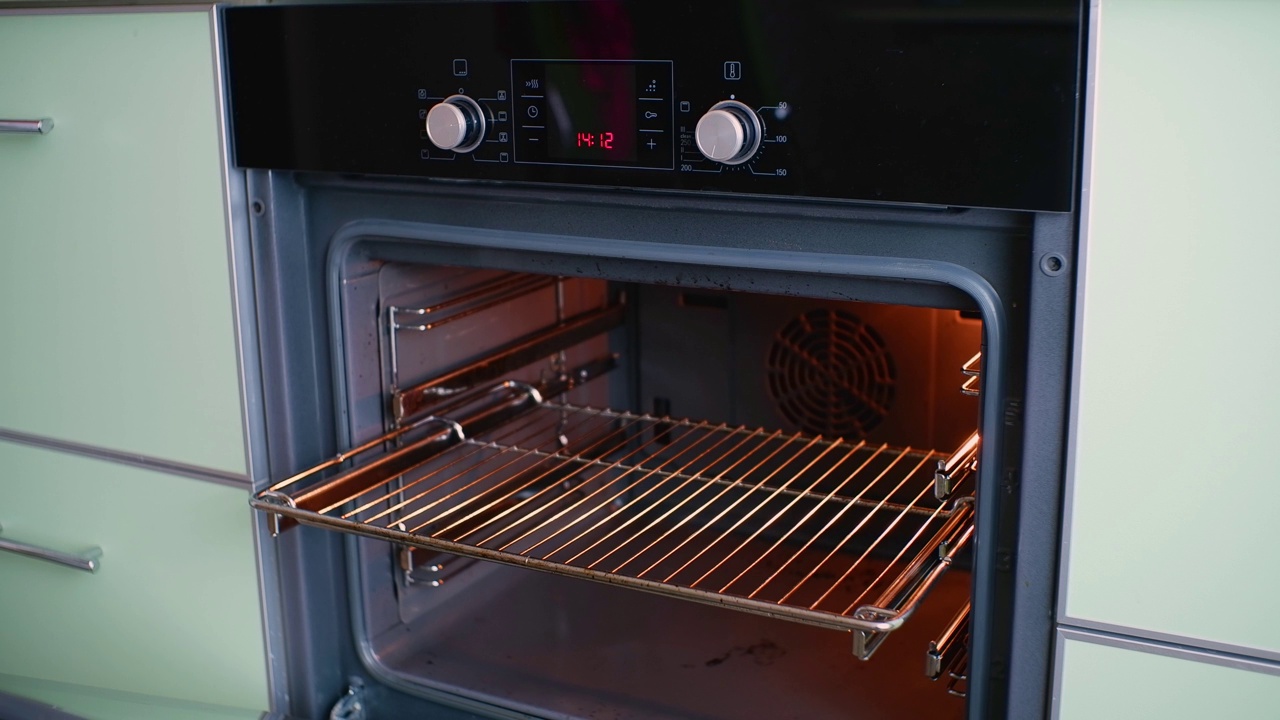 女孩打开烤箱门，拿出一个使用烤箱手套的烤盘。视频下载