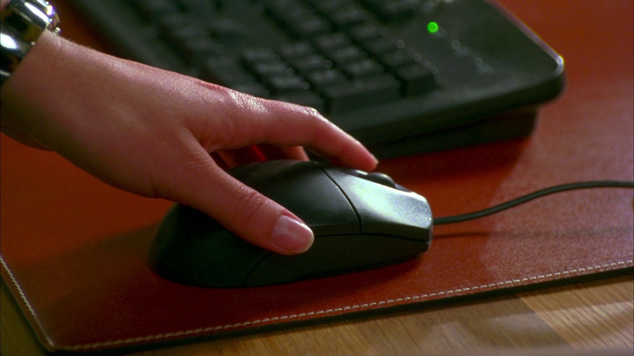 一个女人的手在电脑鼠标上的特写镜头。她单击它。键盘在背景中失焦。可能是办公室。视频下载