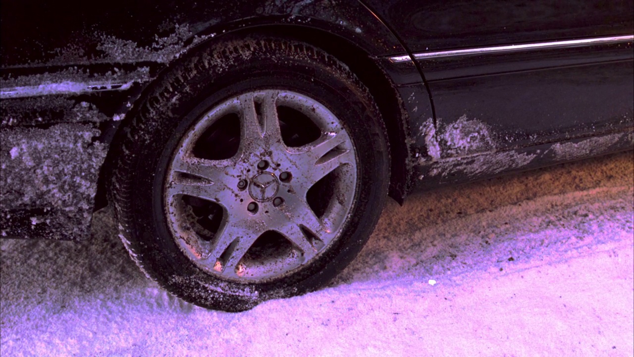 中等角度的汽车轮胎在积雪覆盖的道路或街道上。梅赛德斯-奔驰(mercedes - benz)轮毂。轮胎旋转并起飞。视频下载
