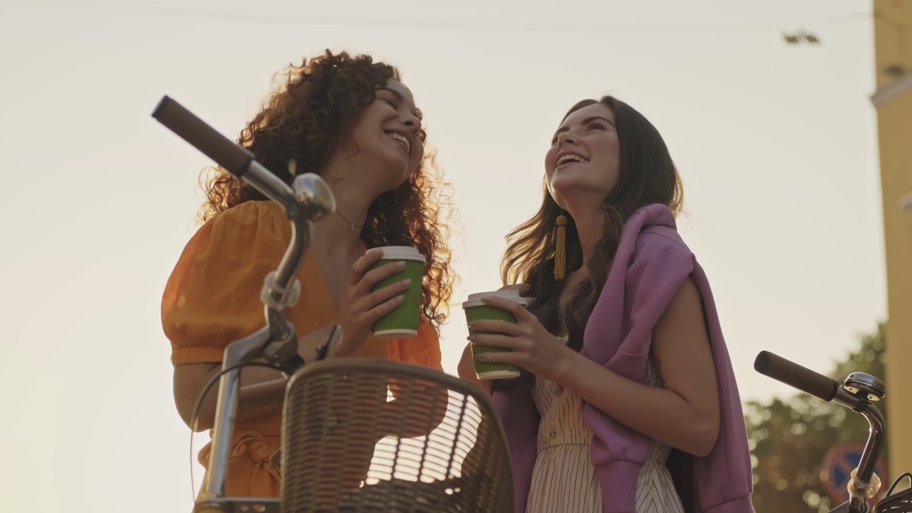 漂亮快乐的年轻女孩朋友们端着外卖咖啡谈笑风生视频下载