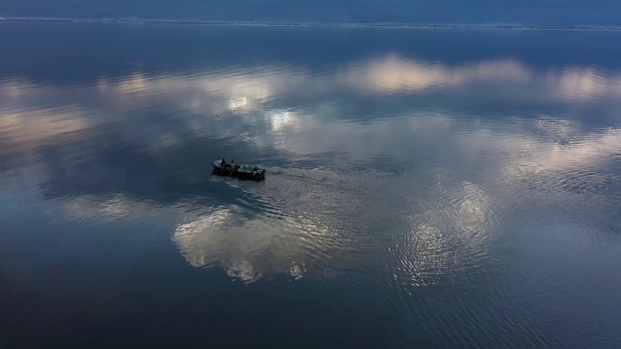 当人们在蓝色的湖面上划着小木船时，云朵和山峦倒映在水中视频下载