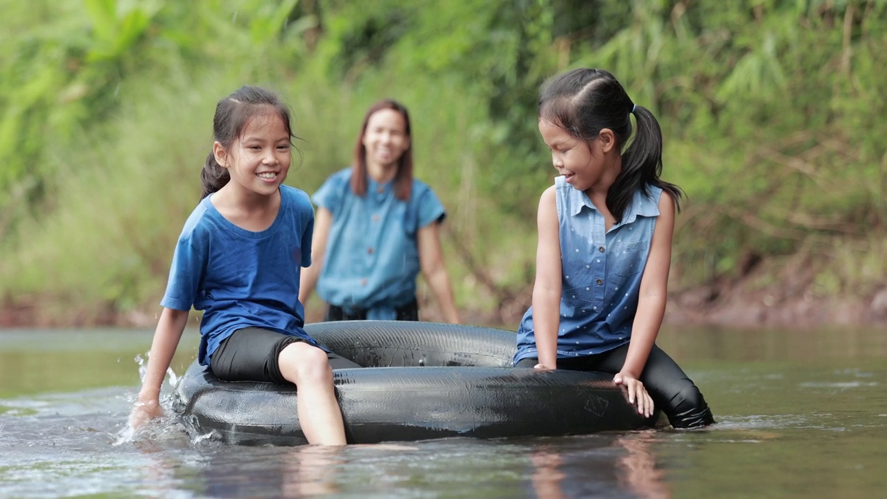 两个亚洲女孩和她们的妈妈在河里玩橡皮圈视频下载
