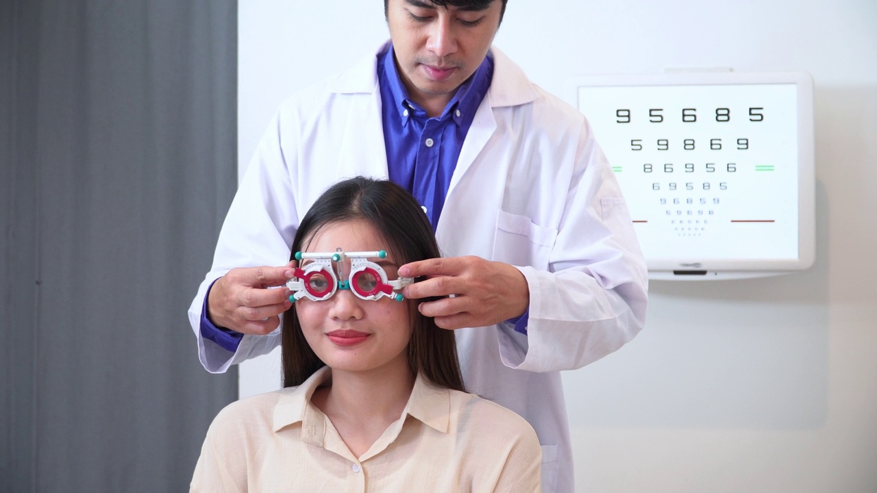 验光师为测试亚洲年轻女性的视力调整距离试架，阅读视力表，Snellen视力表，准备配眼镜，表达积极的情绪，微笑以获得更好的视力视频下载