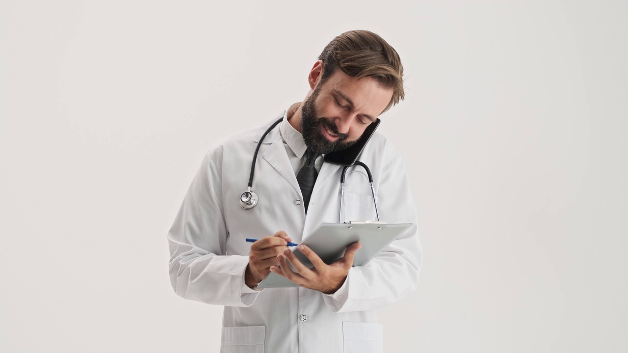 快乐的男人医生与听诊器工作与医疗历史和通话的智能手机视频下载