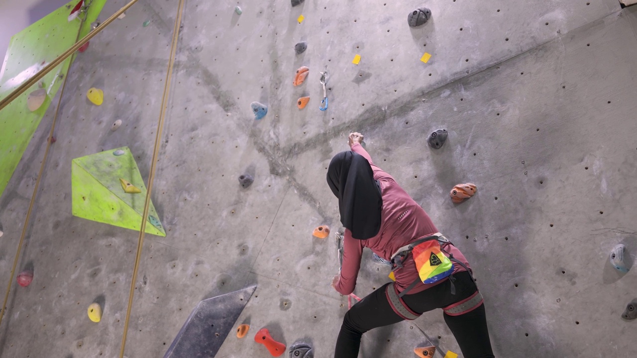 印度尼西亚女性攀岩者用安全安全带爬墙视频下载