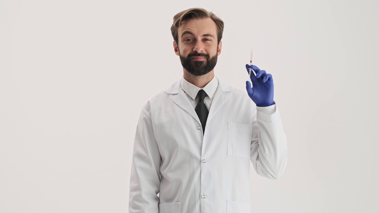 微笑的男人医生和蓝色的手套，拿着注射器视频素材