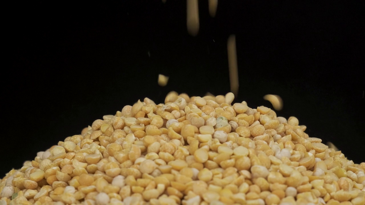 谷物落在一堆豌豆种子上。旋转谷物堆。孤立的视频素材