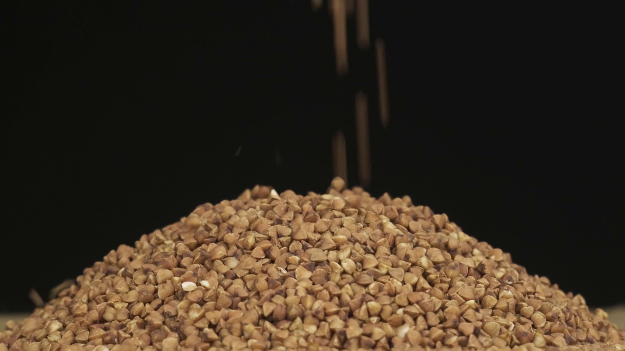 谷物落在一堆荞麦种子上。旋转谷物堆。孤立的视频素材