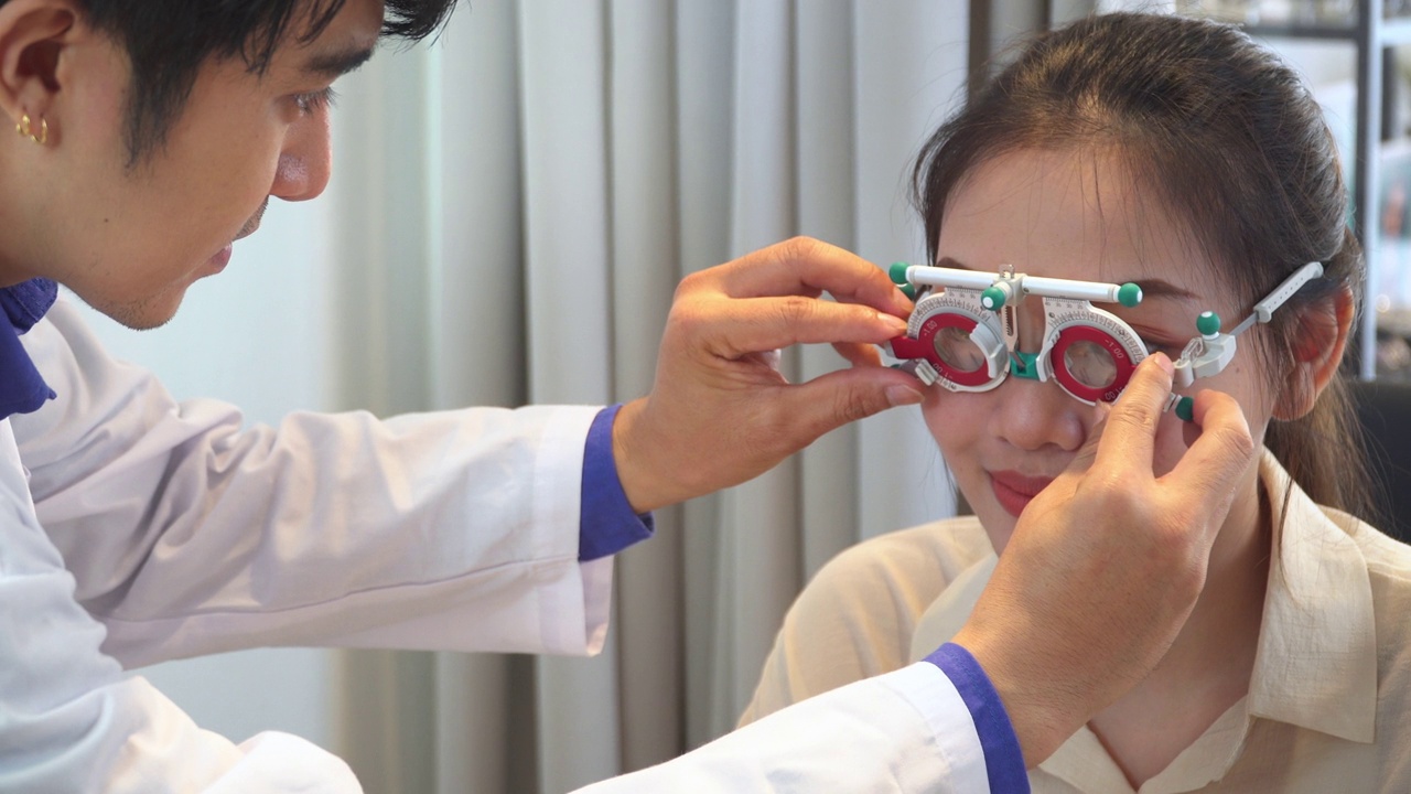 验光师为亚洲年轻女性调整镜头和距离试镜架，准备配眼镜，表达积极的情绪，微笑以获得更好的视力视频下载