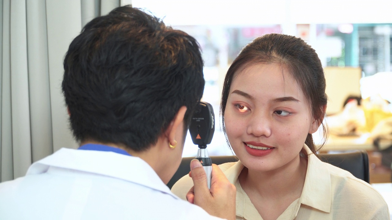 验光师调整视网膜镜和主观屈光的距离，测试亚洲年轻女性的视力，准备配眼镜视频下载