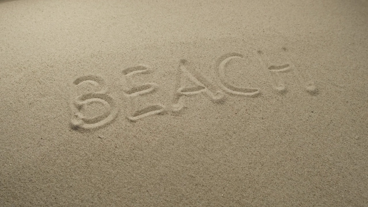 沙滩上写着“海滩”这个词。滑块拍摄视频下载
