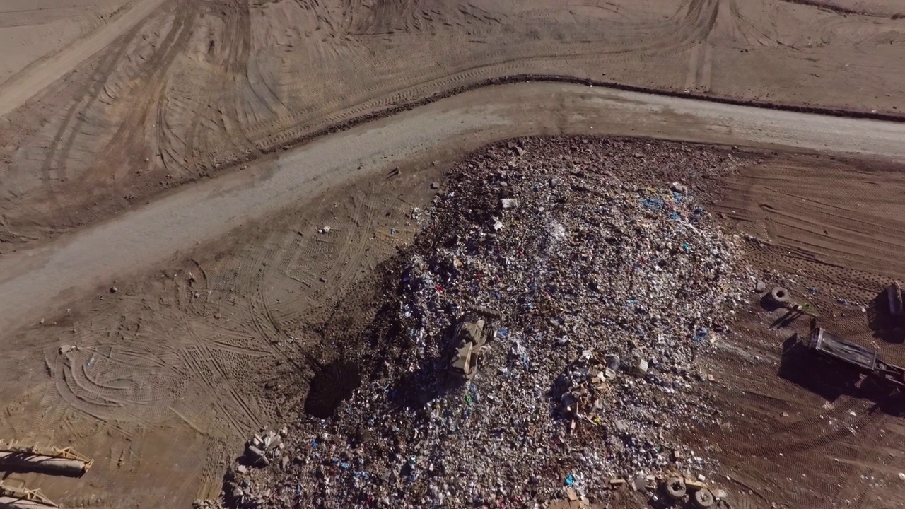 一辆推土机在垃圾填埋场压缩垃圾的航拍照片视频下载