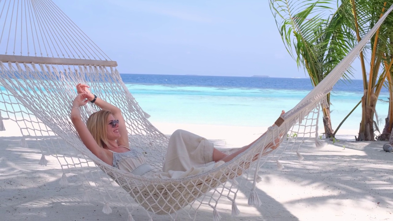 美丽的女人躺在热带海滩的吊床上视频下载