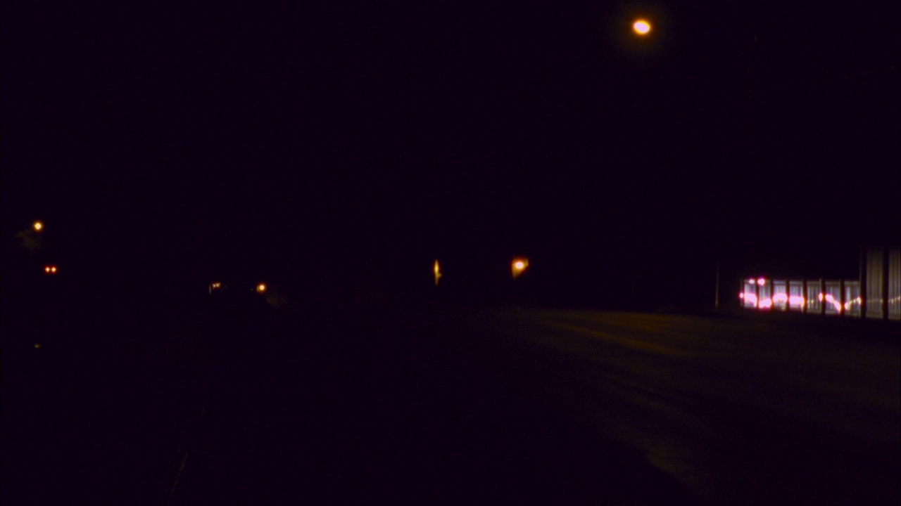 大角度的汽车与前照灯在铺平的道路上行驶，然后从左到右经过pov。路边的雪隐约可见。视频素材