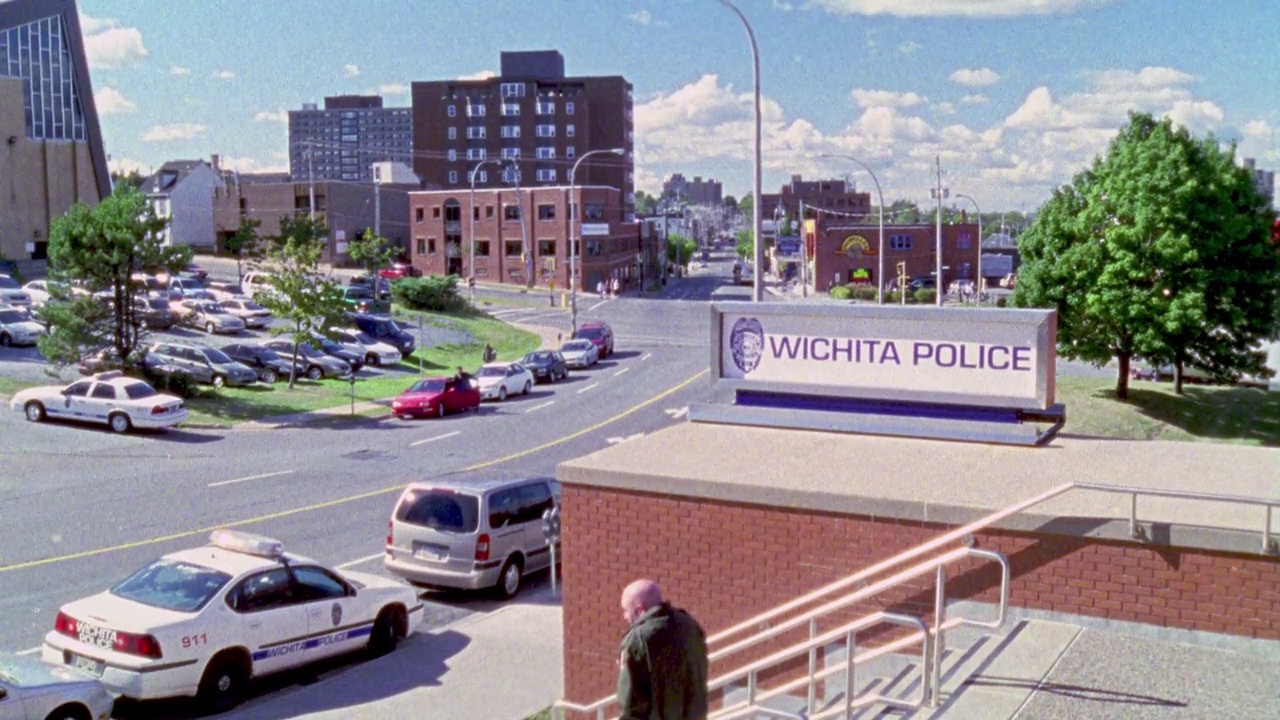 "威奇托警局"站前楼梯的广角镜头。警车停在街上。在bg可见办公大楼。可能在威奇托市中心。视频素材