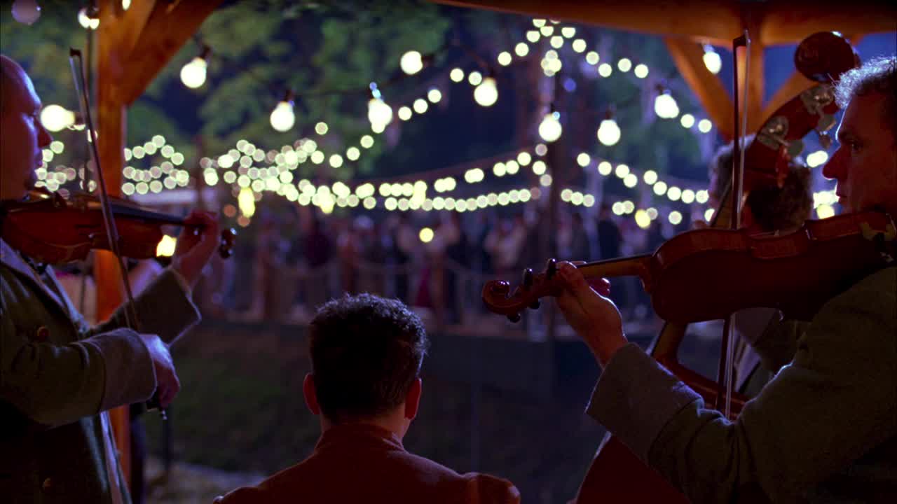 在捷克丰收节的中景中，音乐家在前景中演奏乐器。主要是小提琴或小提琴。人们在一串灯下跳舞喝酒。许多人穿着服装跳传统的民族舞蹈。喝酒。游客和视频素材