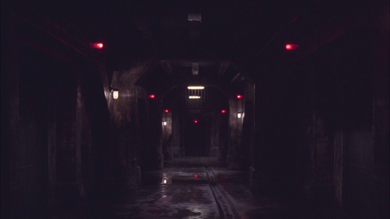 广角拍摄的阴暗诡异的走廊，可能在地下室或仓库里。可能是地下监狱。地下城。门上红灯闪烁。视频下载