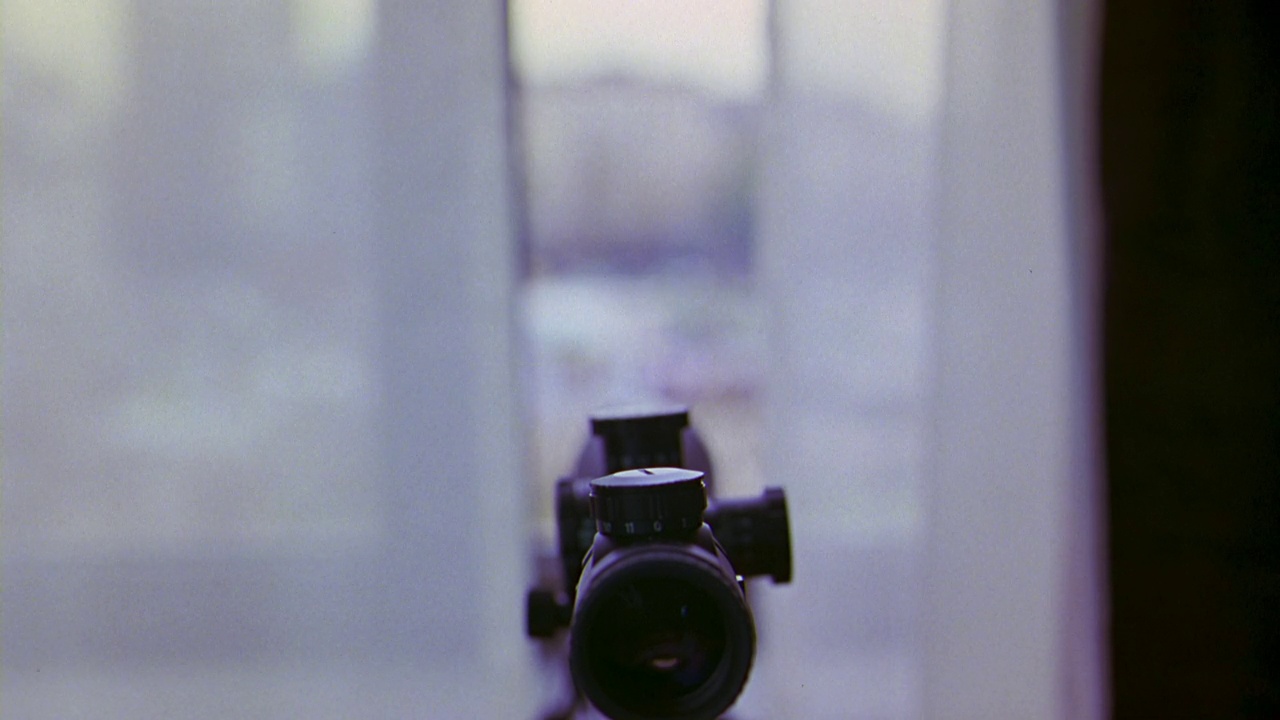 狙击步枪瞄准镜的近角度。步枪指着挂着窗帘的高层窗户。视频下载