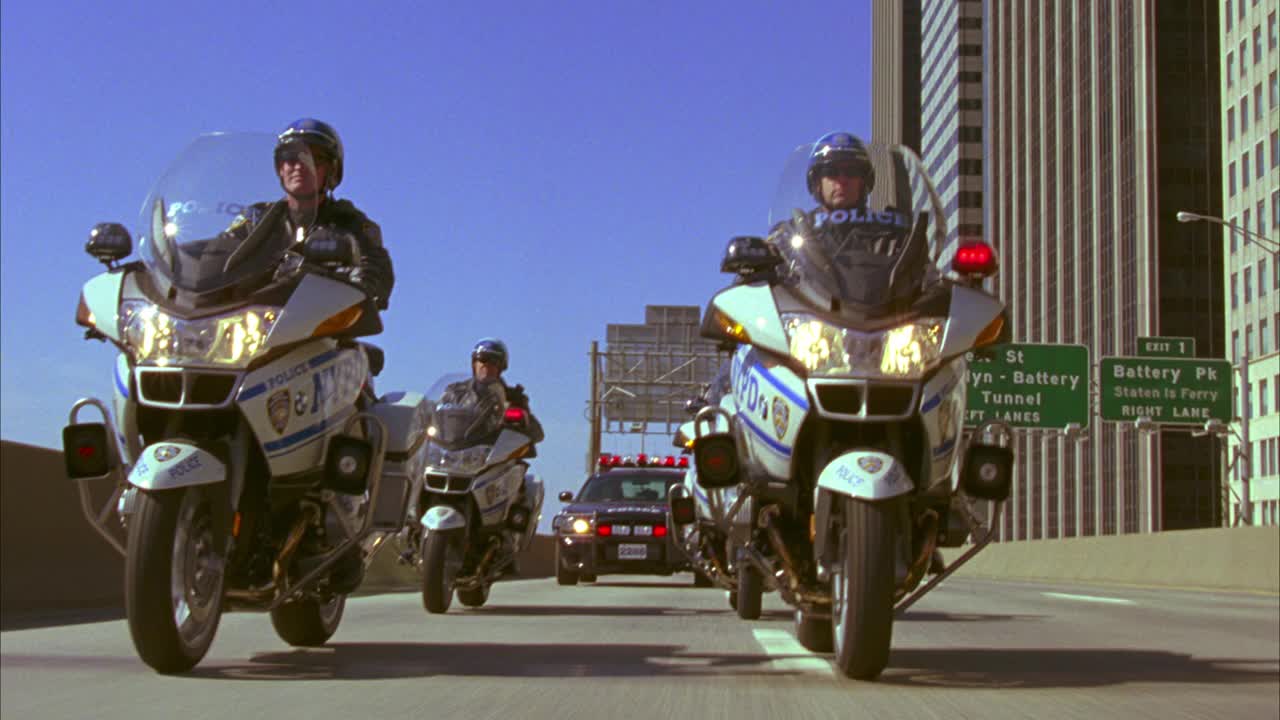纽约警局摩托车在高速公路上护送警车的跟踪镜头。车队驶出纽约街匝道。布鲁克林大桥在bg。闪烁的灯光或bizbars。视频下载