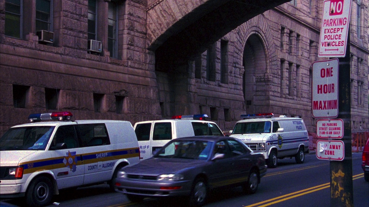 城市街道的中景，背景可能是政府大楼或法院大楼。警车停在大楼旁边，汽车在街上行驶，可能在市中心。视频下载