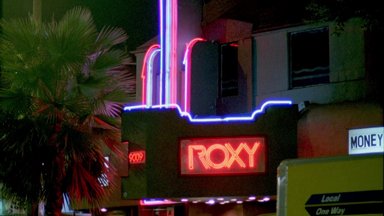 日落大道上的roxy酒吧和音乐俱乐部外面的霓虹灯“roxy”标志的近角度。西好莱坞。棕榈树。汽车在街上行驶。卡车停。日落大道。视频素材