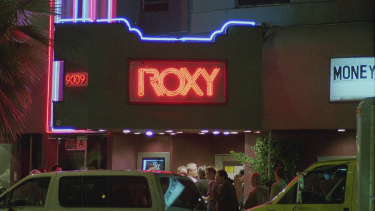 从Roxy酒吧和音乐俱乐部屋顶上的“r”霓虹灯的近角度向下倾斜，并在俱乐部入口处进行标识。人站在外面。汽车在日落大道上行驶。西好莱坞。日落大道。视频下载