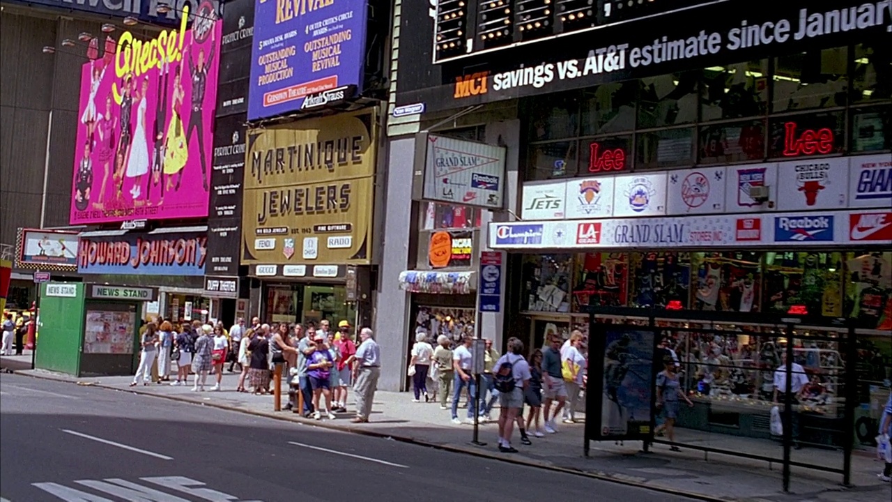 在时代广场行驶的汽车的乘客侧以中角移动。路过悲惨世界，洛克西熟食店，马提尼克珠宝店，豪生酒店的广告牌，还有写着“纽约苹果之旅”的双层巴士。游客在人行道上走过s视频下载