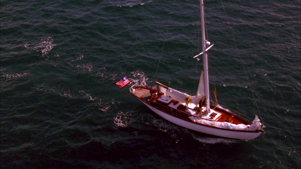 单桅帆船在海洋中上下移动的天线。美国国旗的背面，美国国旗的圆圈里有十三颗星。稍微放大到水中的船。视频素材