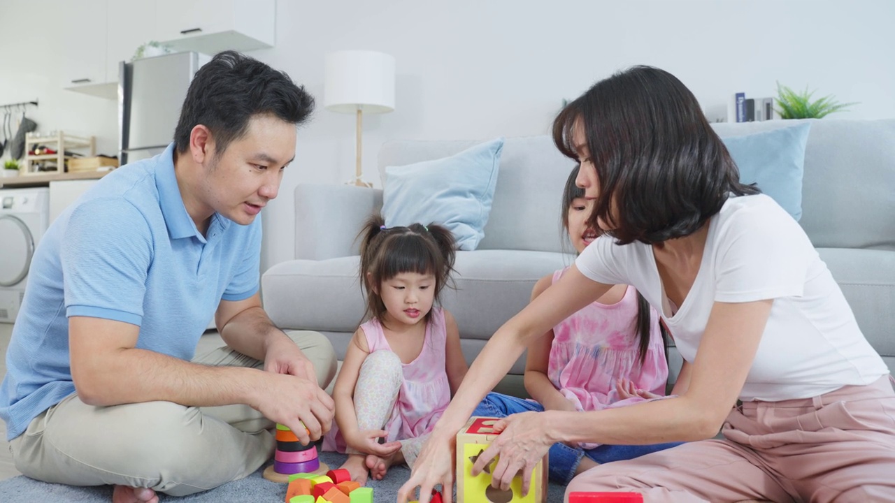 亚洲幸福家庭坐在地板上，在客厅里一起玩玩具。漂亮的父母和父母花时间和年轻的小女孩在家里。家庭活动关系概念。视频下载