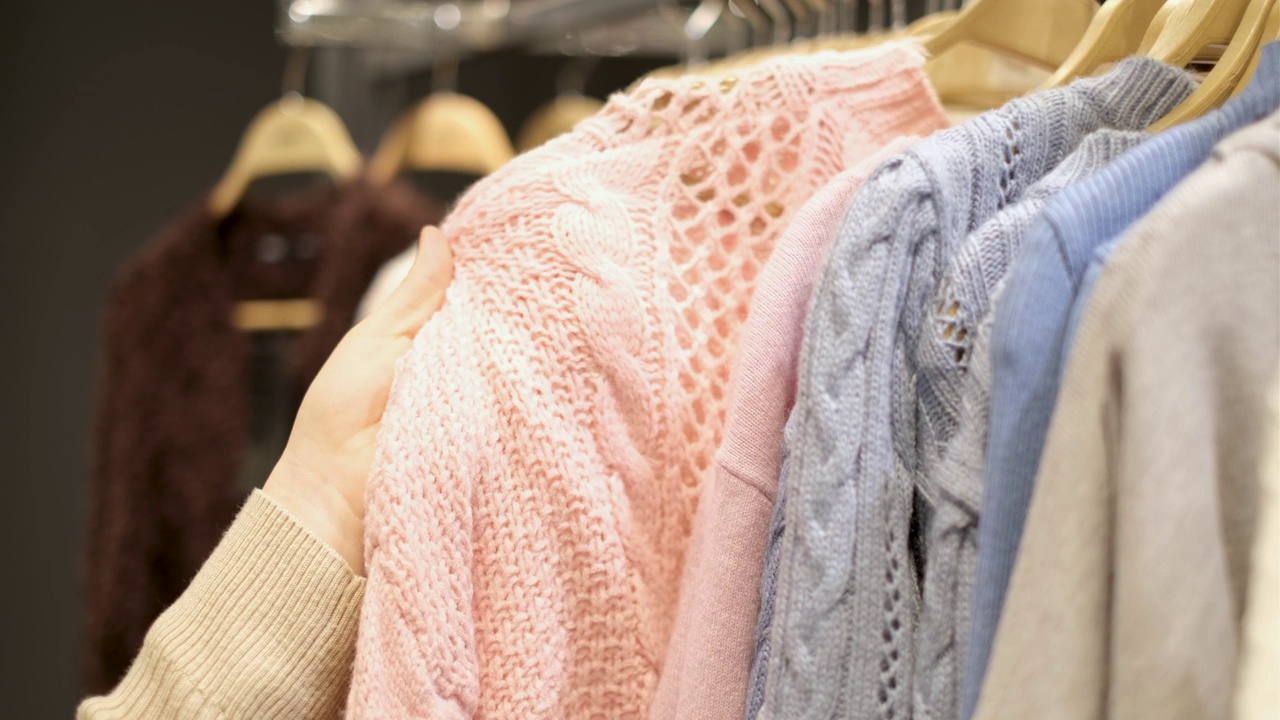 女性手选毛衣在商店服装特写。视频素材