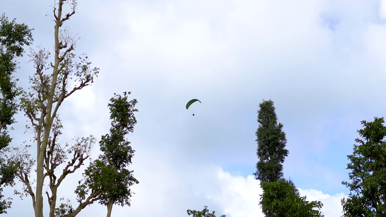 在印度古吉拉特邦的萨普特拉，游客们在空中享受滑翔伞。游客在萨普特拉体验冒险活动。在蓝天白云前跳伞。视频素材