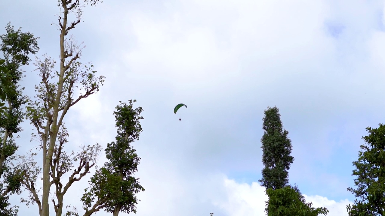 在印度古吉拉特邦的萨普特拉，游客们在空中享受滑翔伞。游客在萨普特拉体验冒险活动。在蓝天白云前跳伞。视频素材