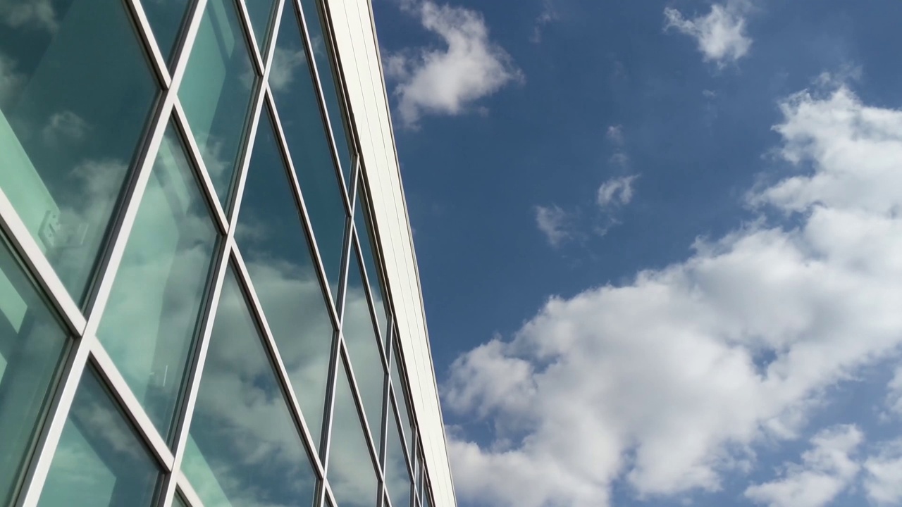 晴空万里，云朵映照在玻璃工业建筑上视频素材