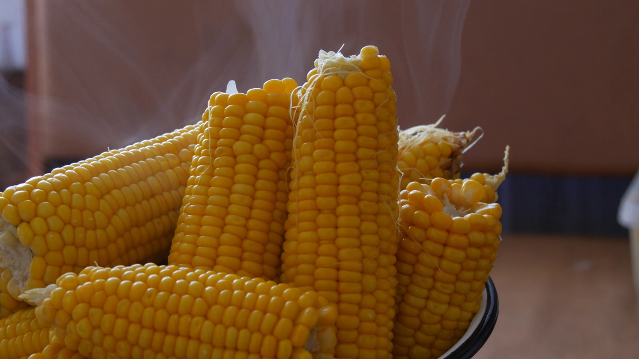 在家里的厨房里用大碗煮玉米。蒸汽出来视频素材
