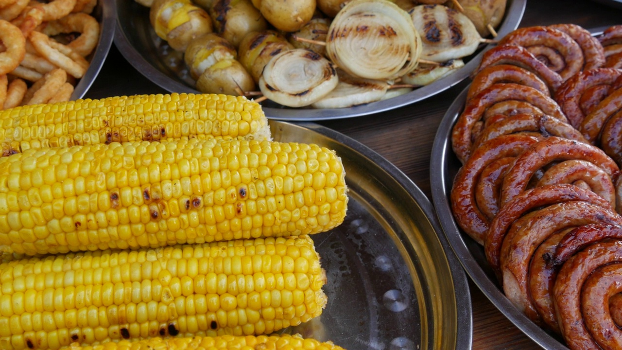 把煮熟的玉米和各种油腻的快餐放在一张丰盛的桌子上视频素材