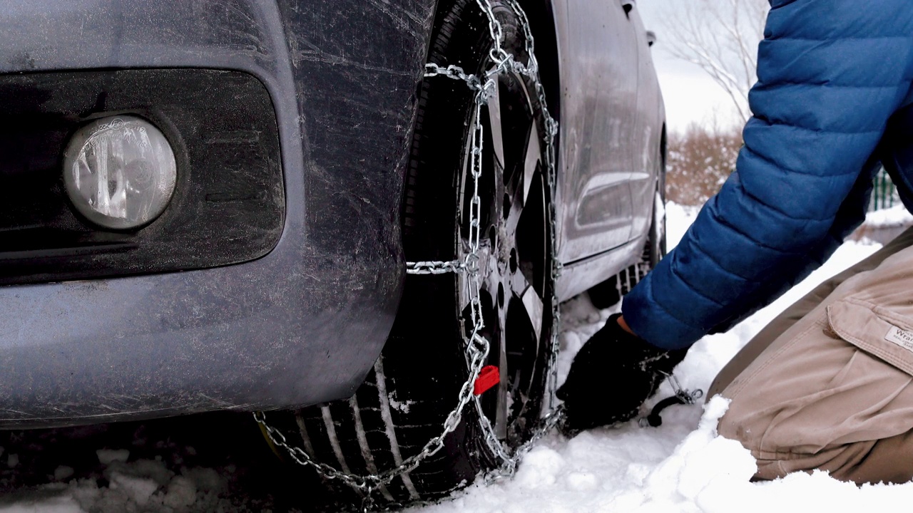 困在雪中的汽车和在轮胎上装雪链的人视频下载