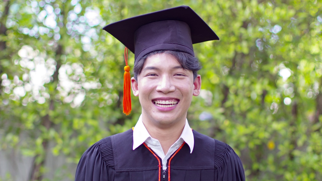 亚洲的毕业生，戴着学士帽，穿着学士服，在毕业典礼上骄傲的微笑和幸福，在毕业典礼上祝贺学生，教育成功的理念视频下载